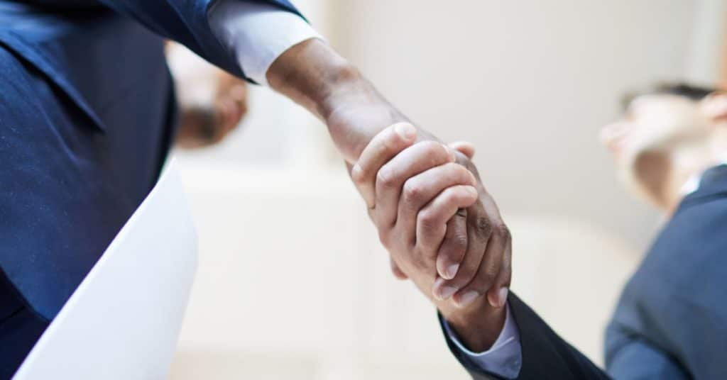 Two people are shaking hands over a public adjuster insurance claim
