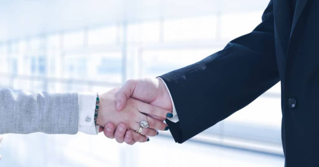 Business professionals shake hands over a public adjuster agreement