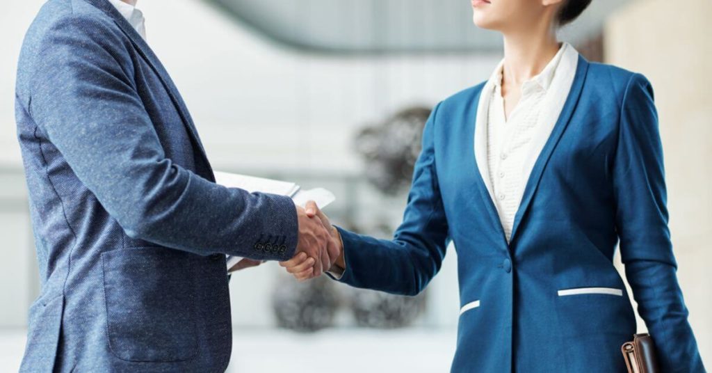 A male and female shake hands over an appraisal clause