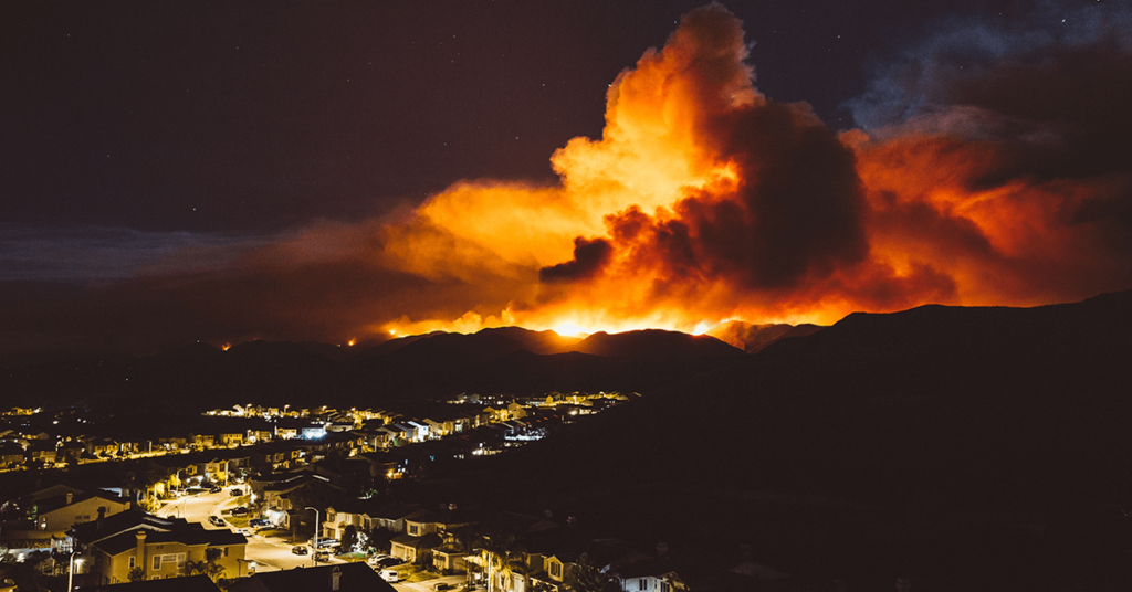 A large wildfire bursting behind a city
