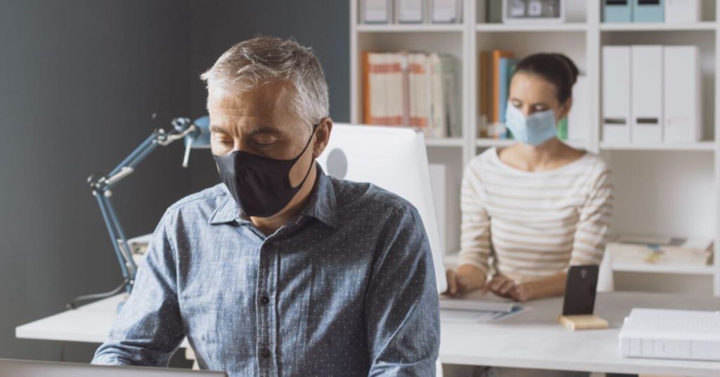 Two office coworkers are working within an office space with face masks on business interruption