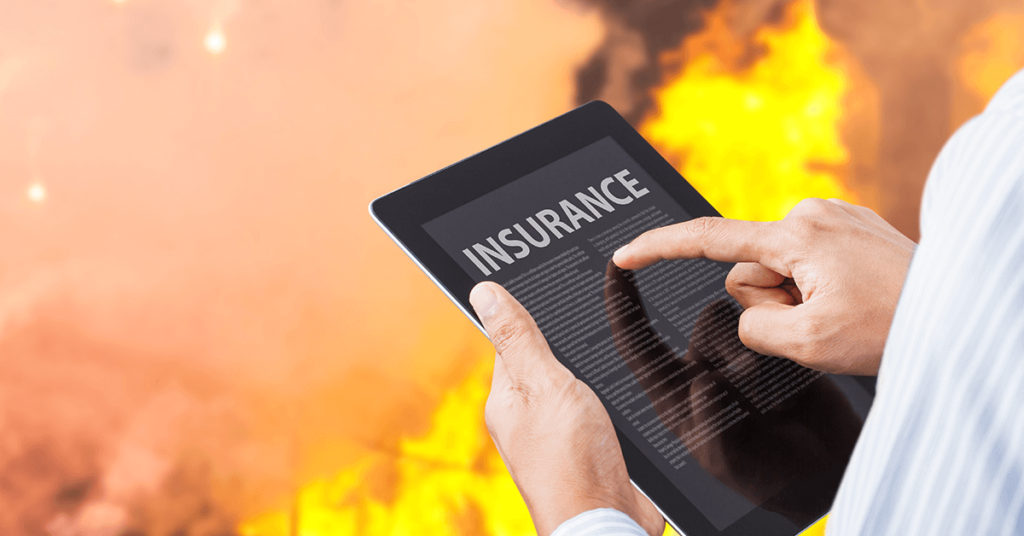 Man pointing at insurance settlement information on tablet with fire background