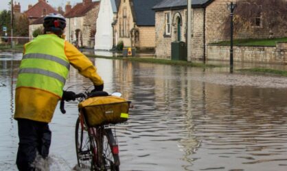 A man is pushing his bike in a flooded town water damage