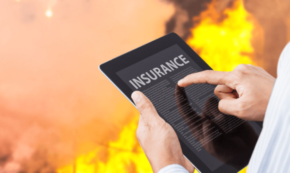 Man pointing at insurance settlement information on tablet with fire background
